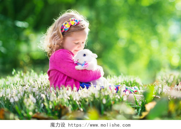 一个沐浴在阳光下抱着小兔子在田野里